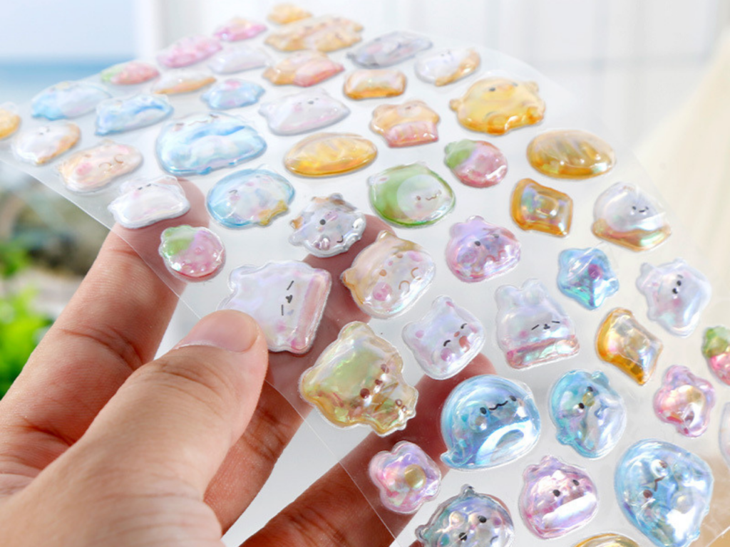 Hand peeling a small bubble sticker from a sheet of raised designs