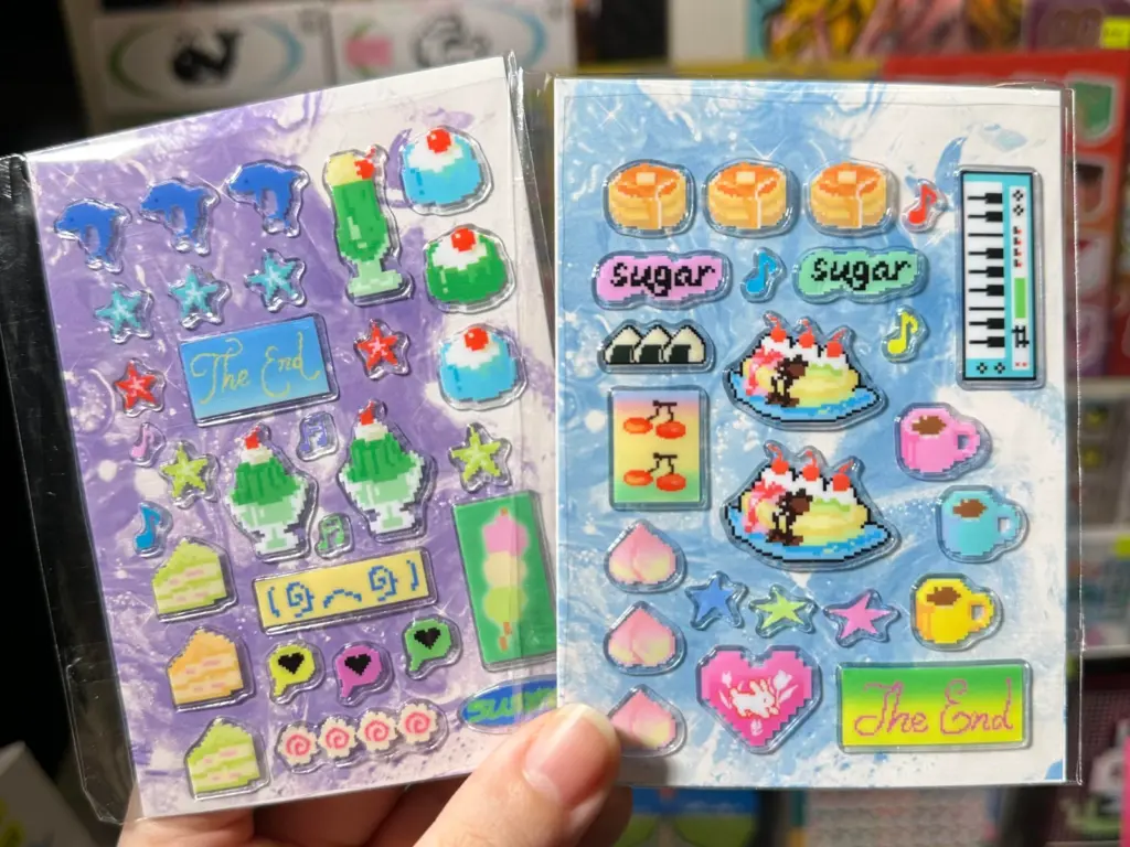 Two clear puffy sticker sheets displayed on contrasting purple and blue printed backing cards.